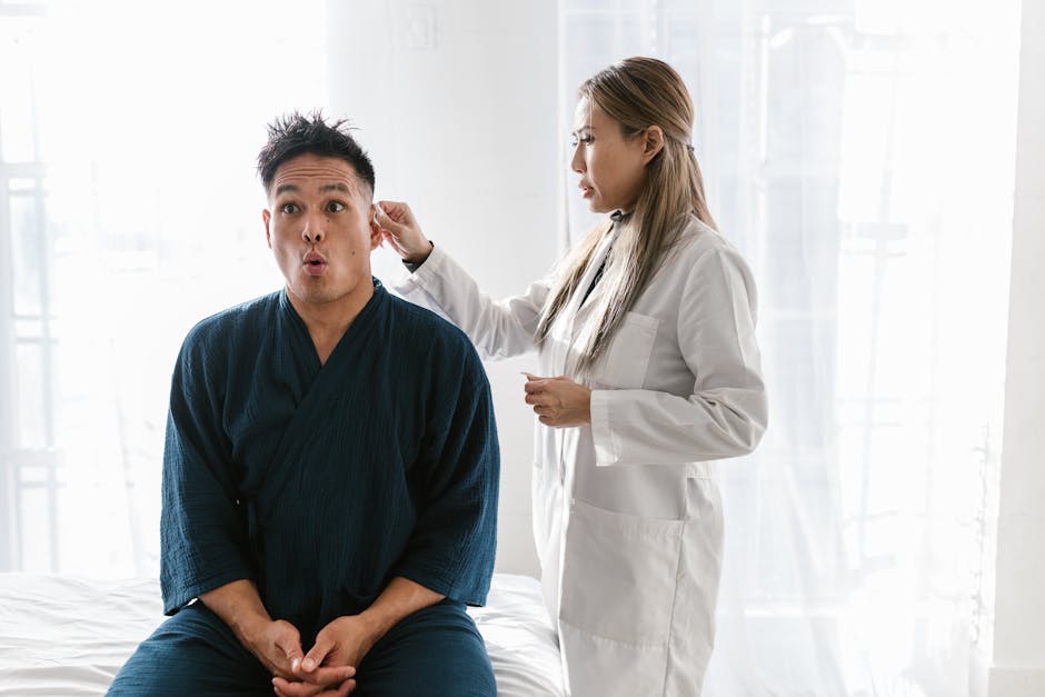 A doctor in a white coat conducts an ear exam on a patient indoors.