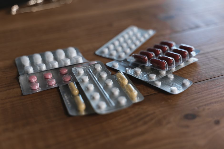 A variety of pills in blister packs displayed on a wooden surface. Ideal for health-related content.