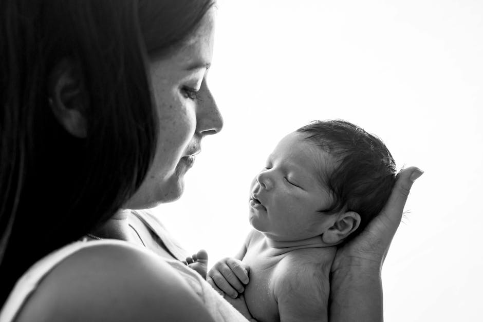Black and white portrait of a mother lovingly holding her newborn.