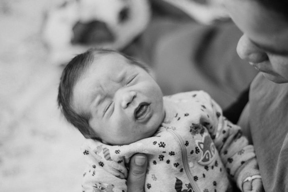 Tender black and white moment of a newborn held closely by the mother.